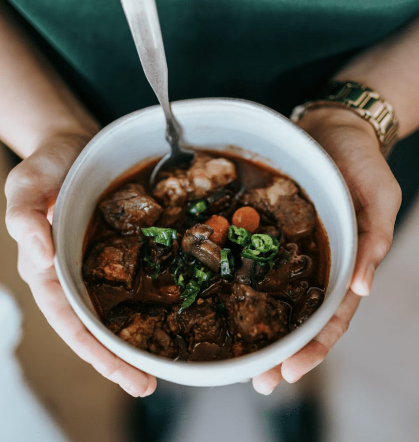 A Woman holding a white bowl containing soup