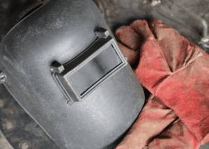 Black welding helmet and red welding gloves