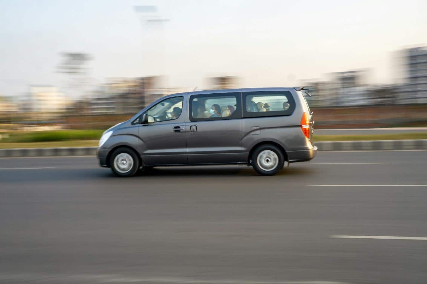 A grey van moves quickly down the road.