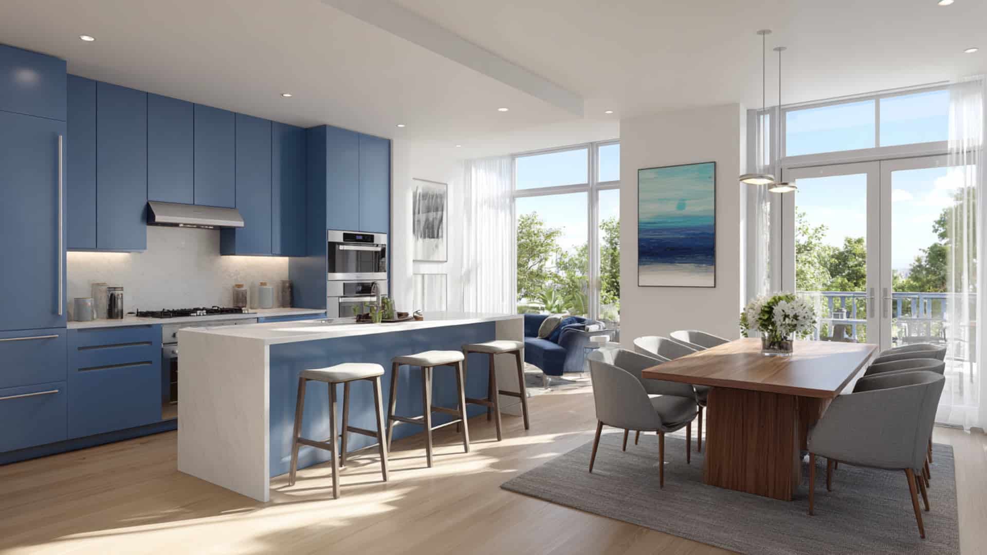 Modern open-plan kitchen and dining area with matte blue cabinets, white island, bar stools, and large bright windows.