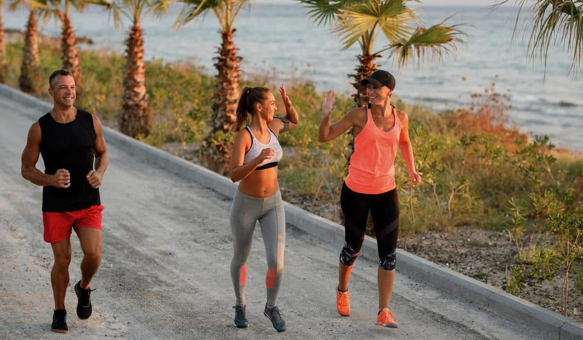 Smiling people jogging and high-fiving on a coastal path
