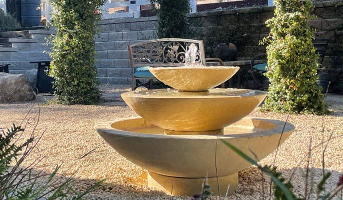 Three-tiered stone water fountain in a gravel courtyard