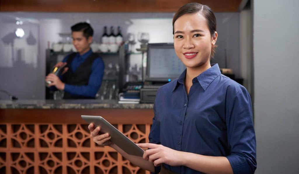Restaurant manager using digital tablet with bartender in background