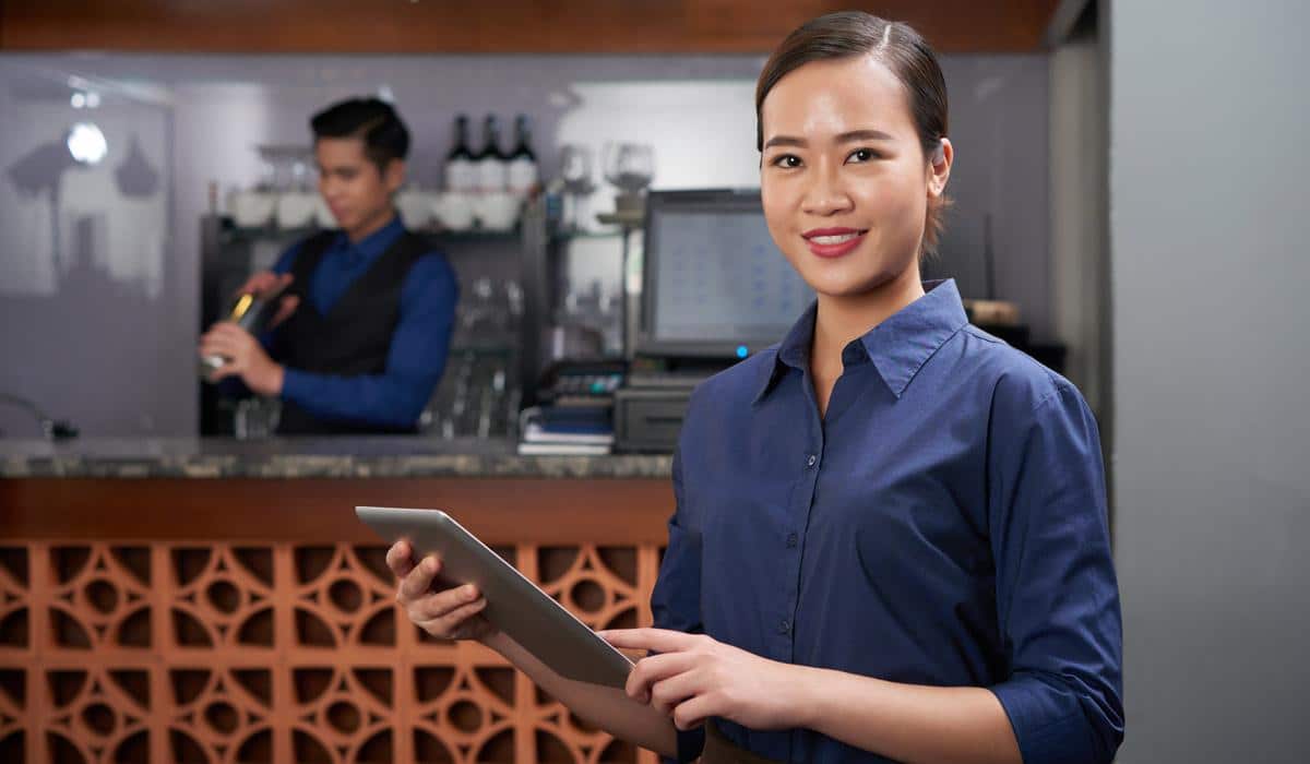 Restaurant manager using digital tablet with bartender in background