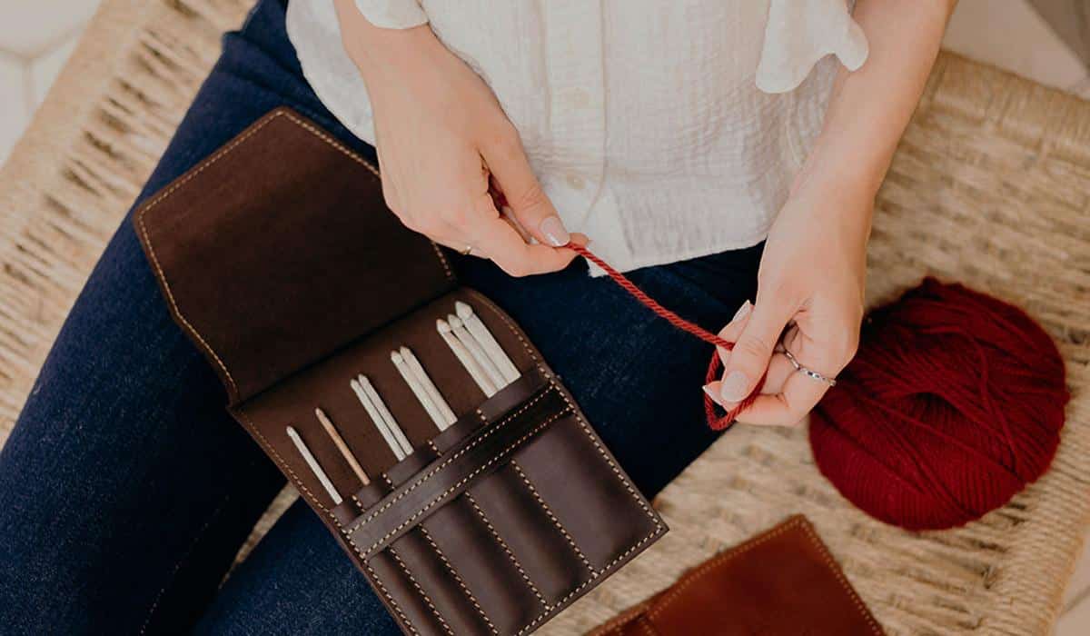 Person holding red yarn with leather crochet hook case