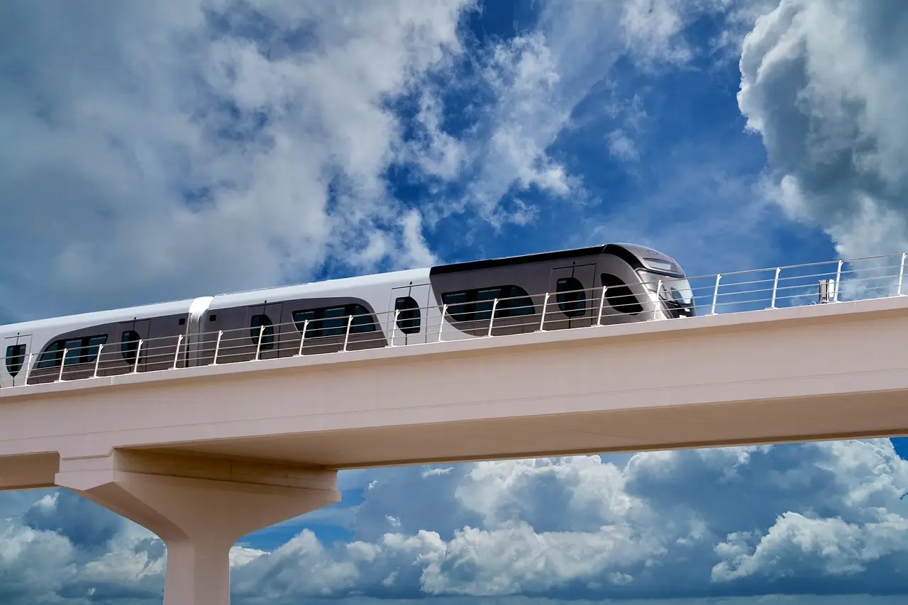 Modern monorail train on elevated track against cloudy blue sky