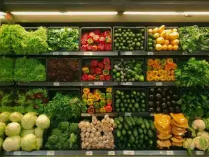 Assorted vegetables neatly arranged on grocery store shelves under bright lighting