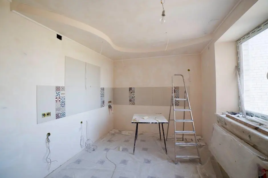 Unfinished kitchen renovation with bare walls, tile accents, and metal ladder in bright natural light