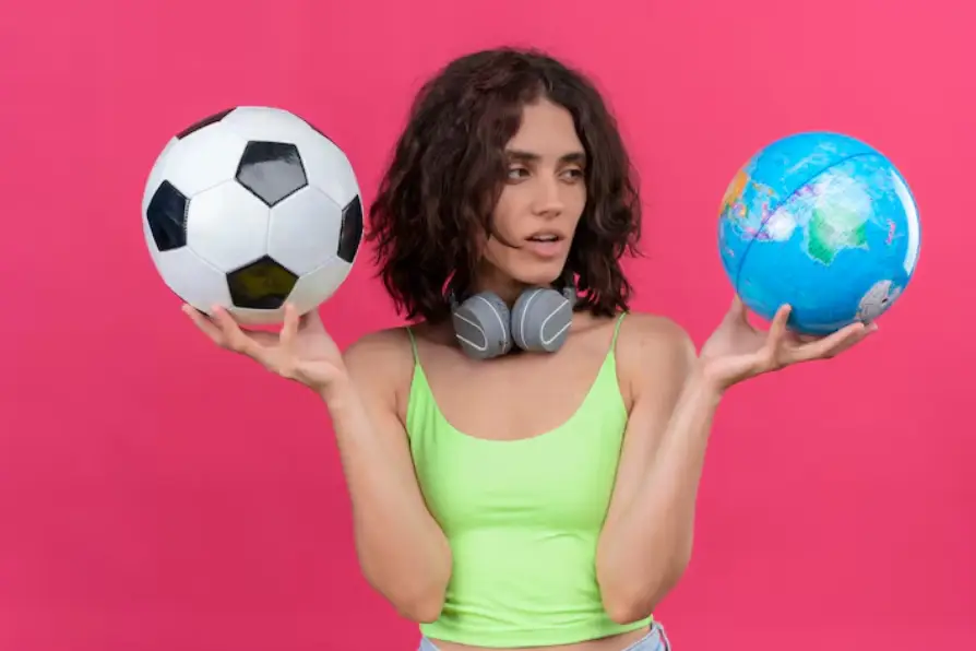 Young woman holding soccer ball and globe against vibrant pink background