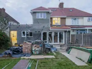 House under renovation with scaffolding, bricks, and building materials in a backyard construction site