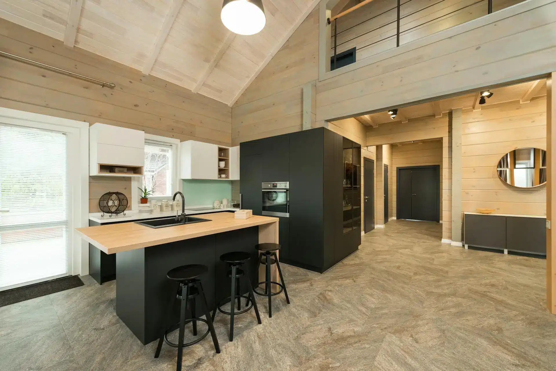 Modern kitchen with wooden island and bar stools in a light wood-paneled room