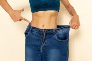 Woman in blue jeans showing weight loss by pulling waistband from body