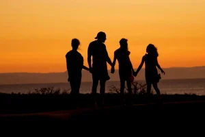Silhouette of a family holding hands at sunset on the beach.