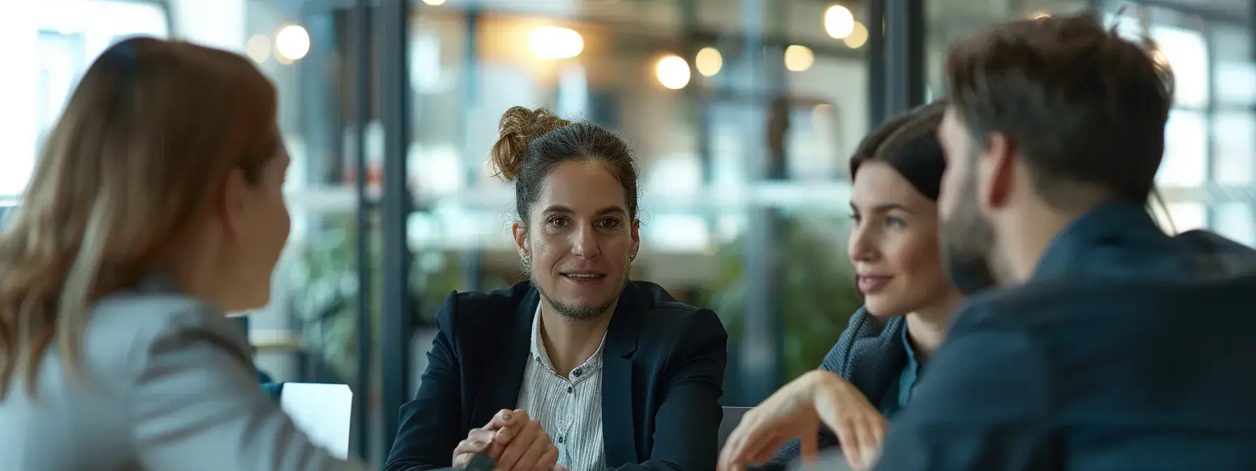 Small group in conversation at a modern office table with blurred background