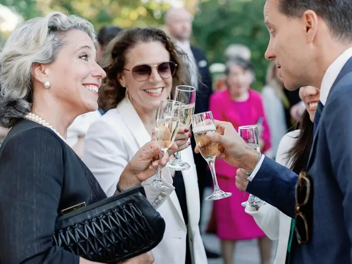 Group of people clinking champagne glasses at an outdoor social event