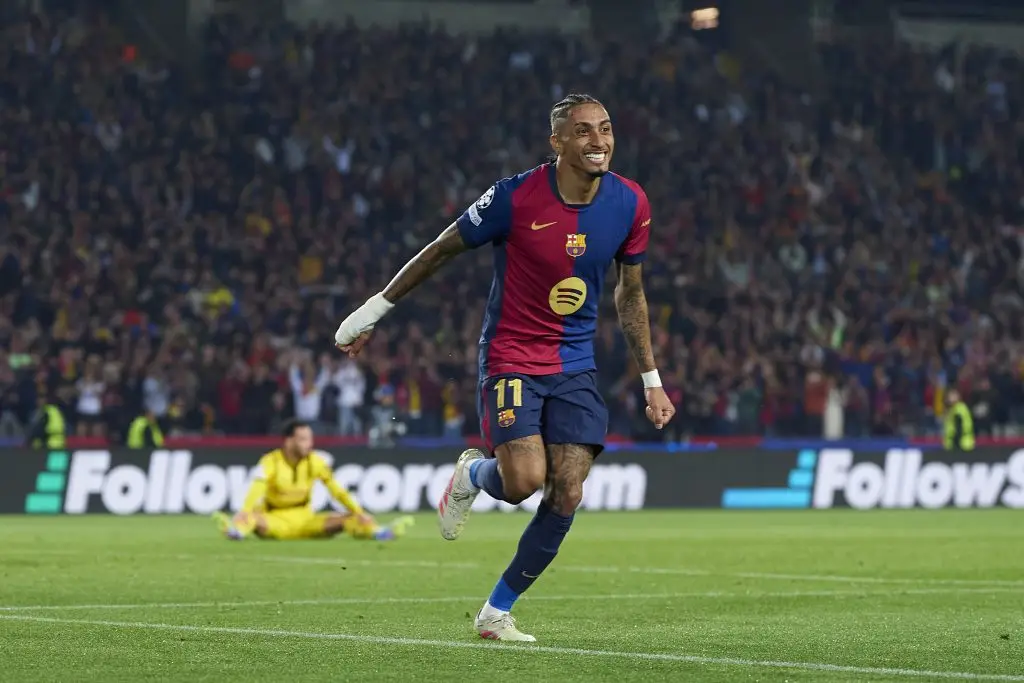 Soccer player celebrating goal on field with cheering crowd in background