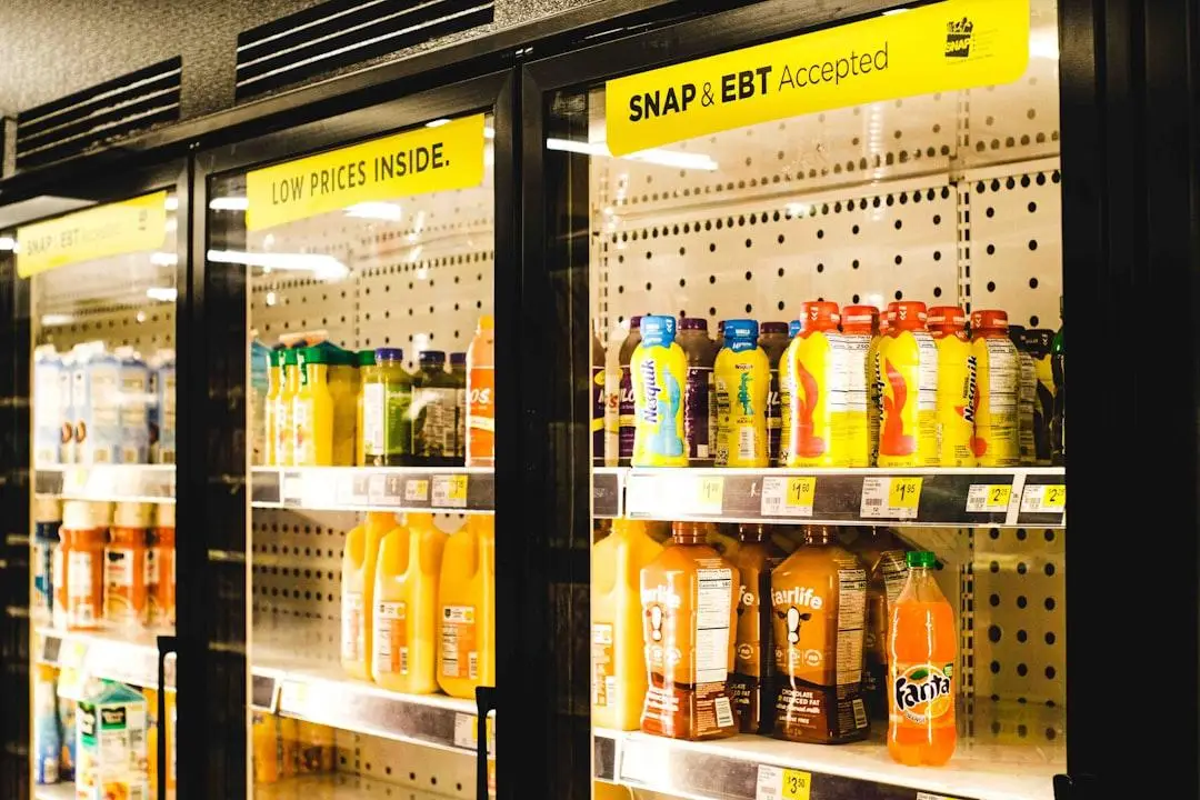 Bottled drinks displayed in refrigerated grocery section with SNAP and EBT sign overhead