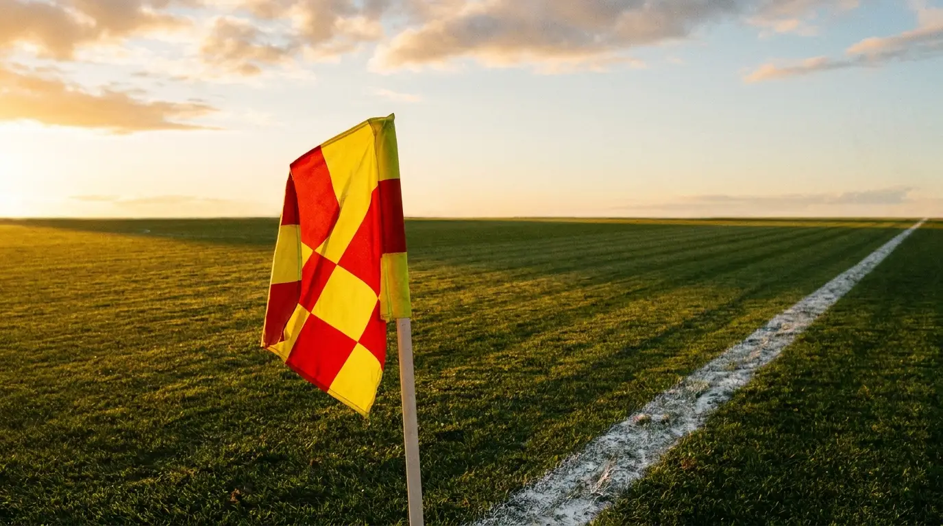Red and yellow checkered flag on soccer field at sunset with white boundary line
