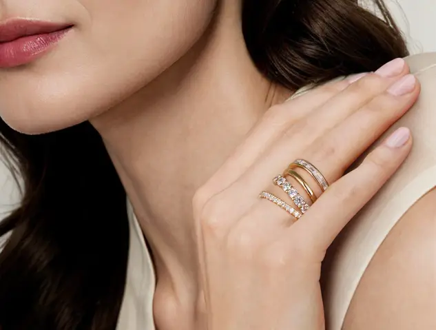 Elegant gold and silver rings with diamonds on woman's hand in soft lighting