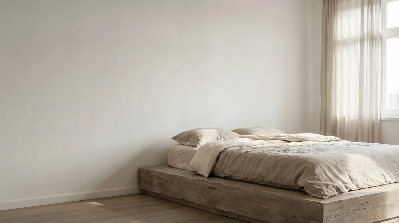 Minimalist bedroom with wooden platform bed and beige linens near large window with curtains