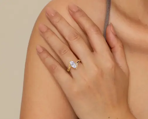 Gold ring with marquise-cut diamond on hand with neutral nail polish