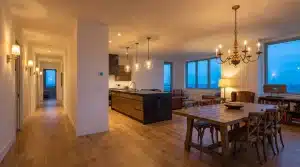 Open-concept living area with wooden dining table and chairs under warm ambient lighting