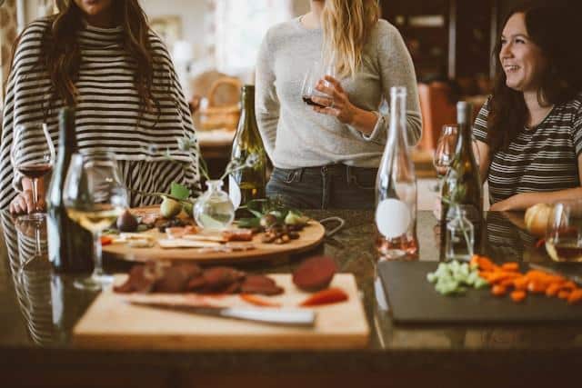 Friends gathered around a kitchen island with wine and charcuterie boards
