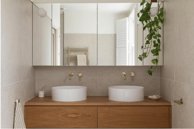 Double sink vanity with round basins and brass faucets in modern bathroom setting