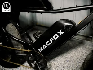 Electric bike frame with visible battery and thick treaded tires in a dim garage setting