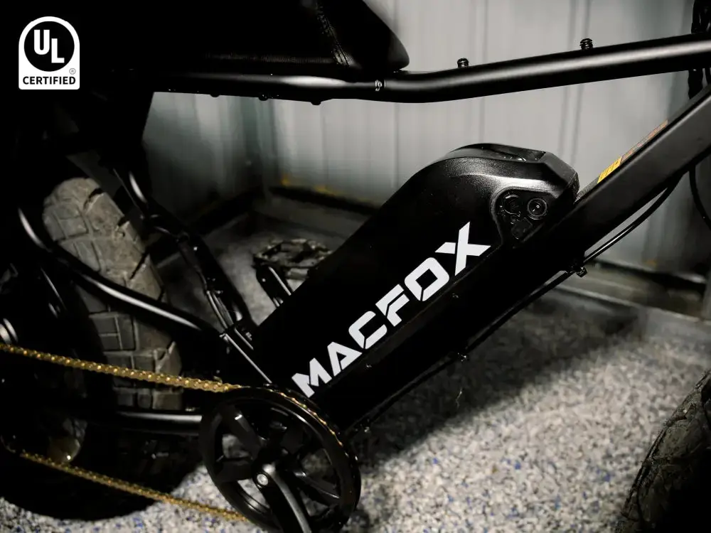 Electric bike frame with visible battery and thick treaded tires in a dim garage setting