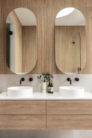 Double vanity with white sinks and black fixtures in modern bathroom with wood paneling