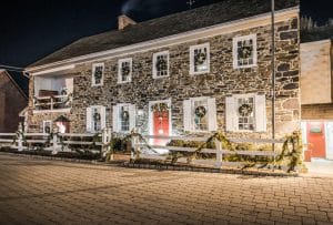 Historic stone building with holiday wreaths and garlands at night, warm lighting and cobblestone path