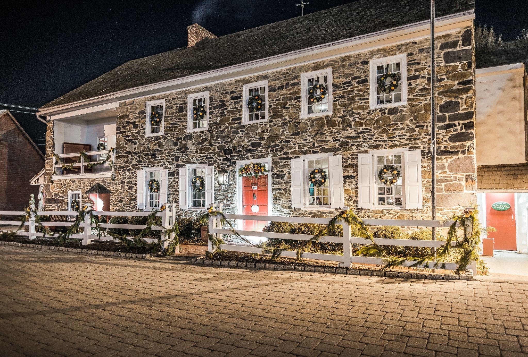 Historic stone building with holiday wreaths and garlands at night, warm lighting and cobblestone path