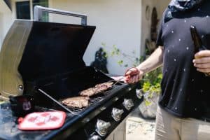 Man grilling steak on outdoor gas grill in sunny patio setting
