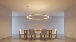 Modern dining room with wooden table, six beige chairs, and circular pendant light fixture