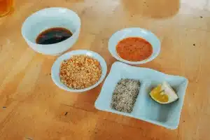 Assorted dipping sauces and condiments in white bowls on wooden table
