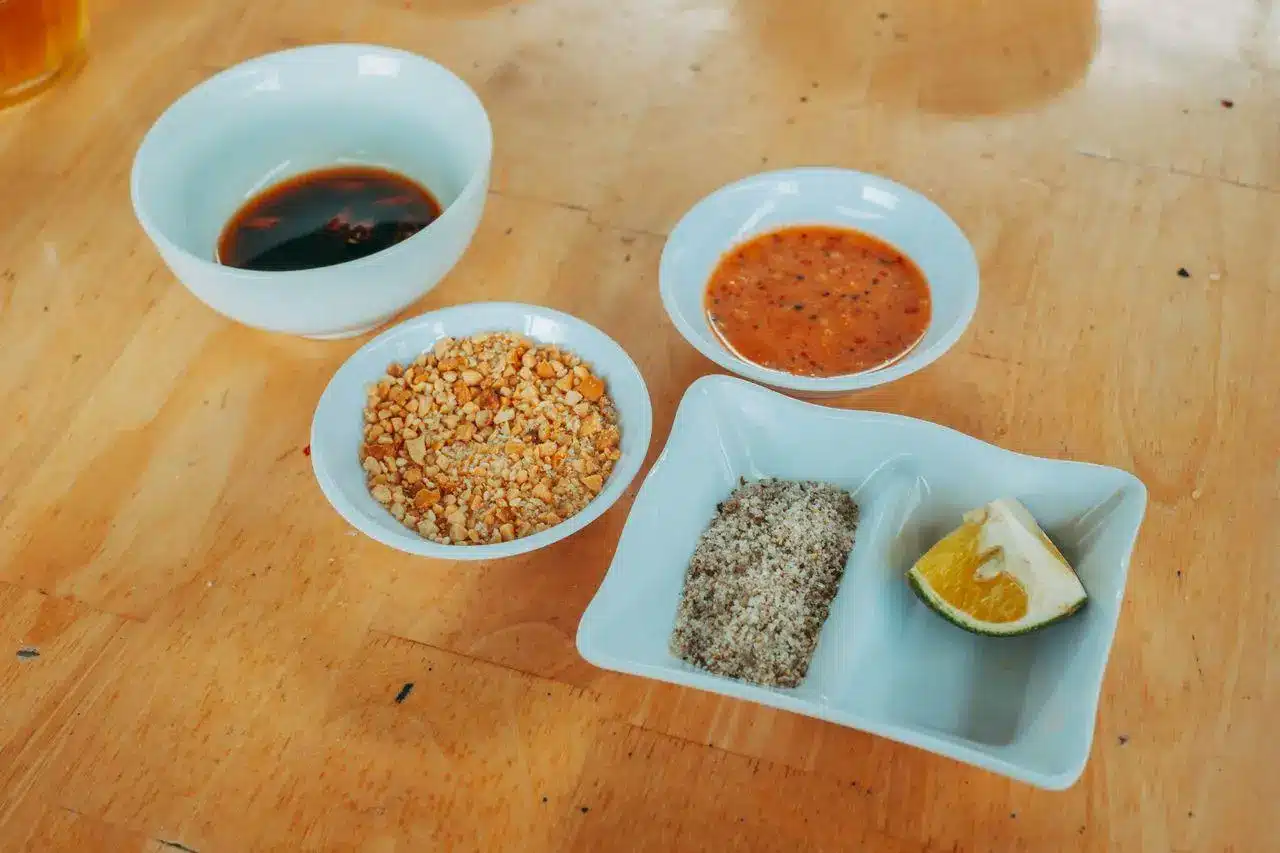 Assorted dipping sauces and condiments in white bowls on wooden table