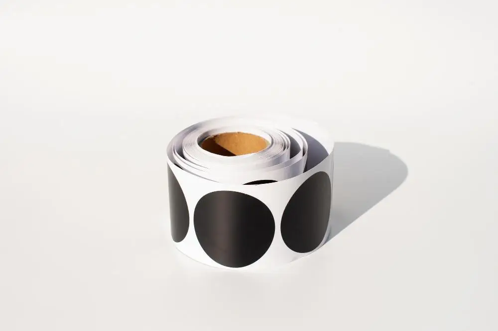 Roll of large black dot stickers on a white background in bright lighting