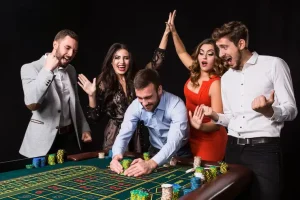 Group of excited people celebrating win at casino table with poker chips