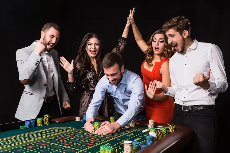 Group of excited people celebrating win at casino table with poker chips