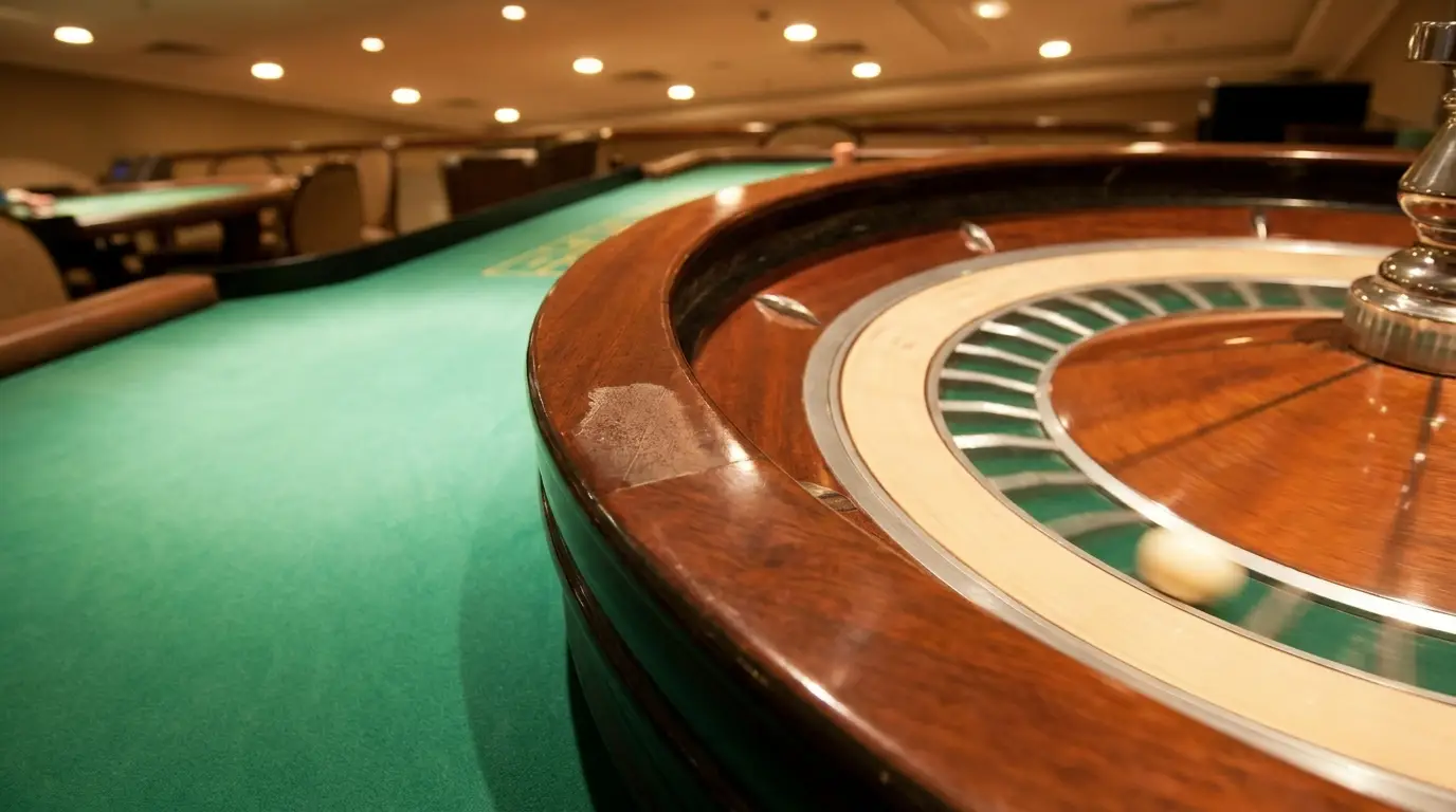Roulette wheel spinning in a casino with green felt tables and chairs in the background
