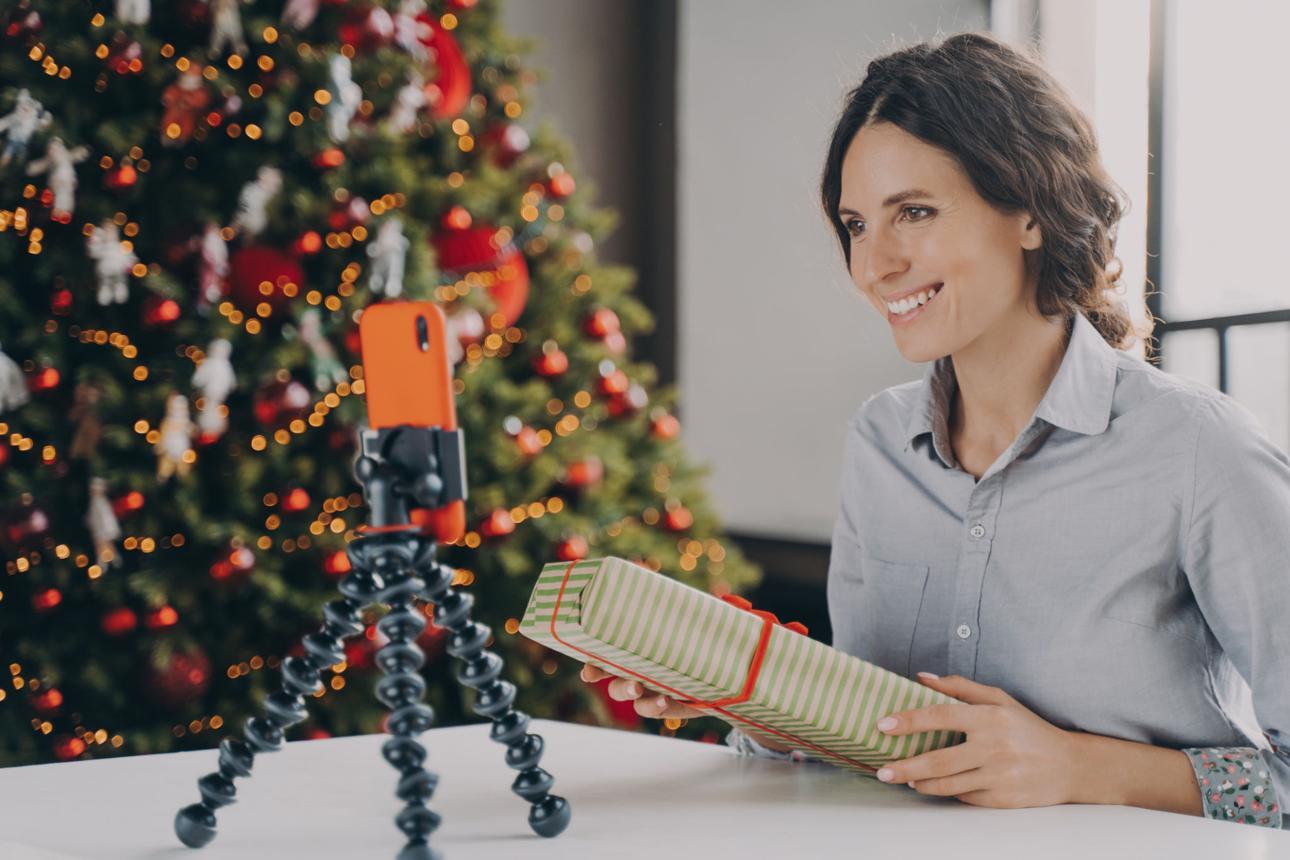 Smiling positive female blogger recording video tutorial about tips for wrapping Christmas presents