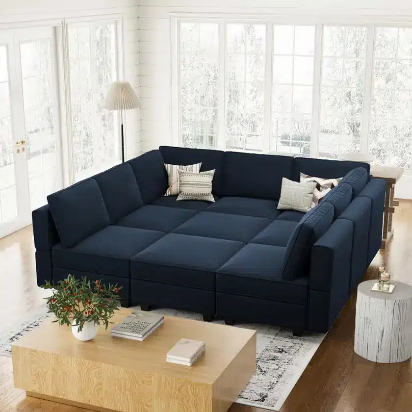 Large navy sectional sofa with decorative pillows in a bright living room with wooden floors