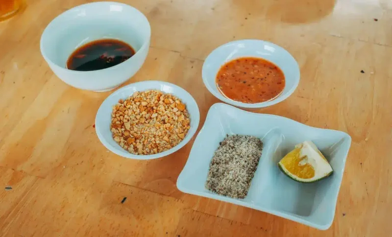 Assorted dipping sauces and condiments in white bowls on wooden table