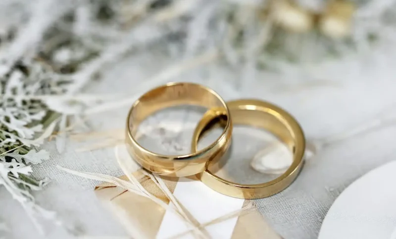 Two gold wedding rings on textured white fabric with floral design