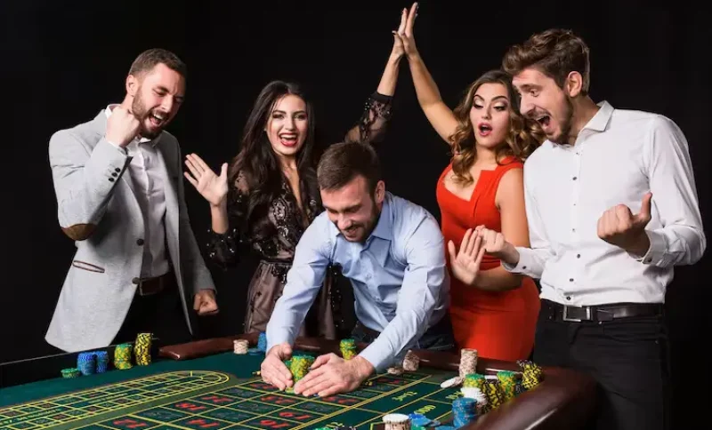 Group of excited people celebrating win at casino table with poker chips