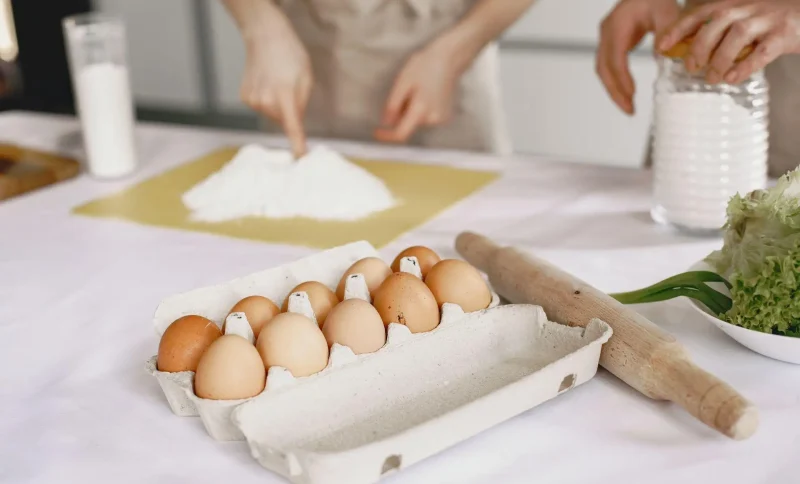 Carton of eggs with rolling pin and flour on kitchen counter